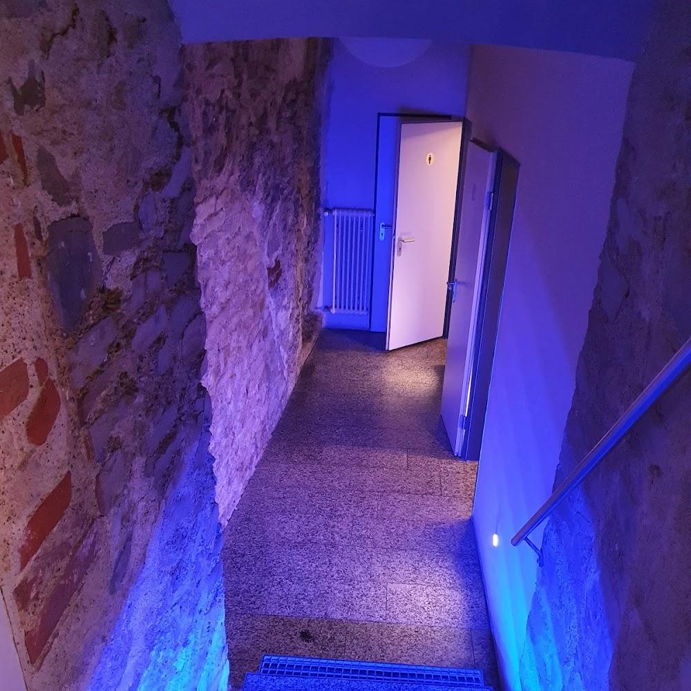 Stone wall hallway with blue lighting and a door.